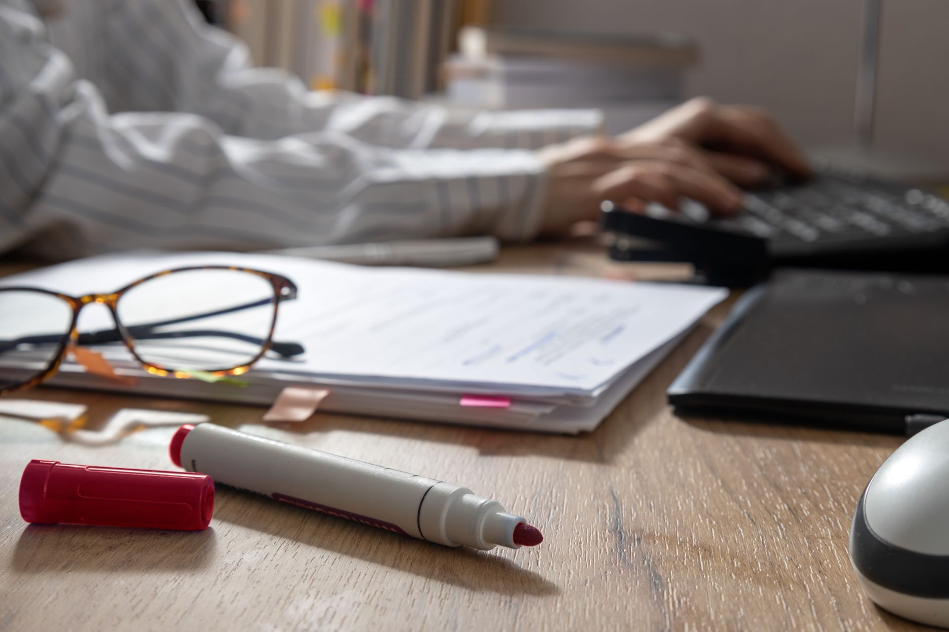 Rotstift und Brille auf einem Schreibtisch bei der Textkorrektur