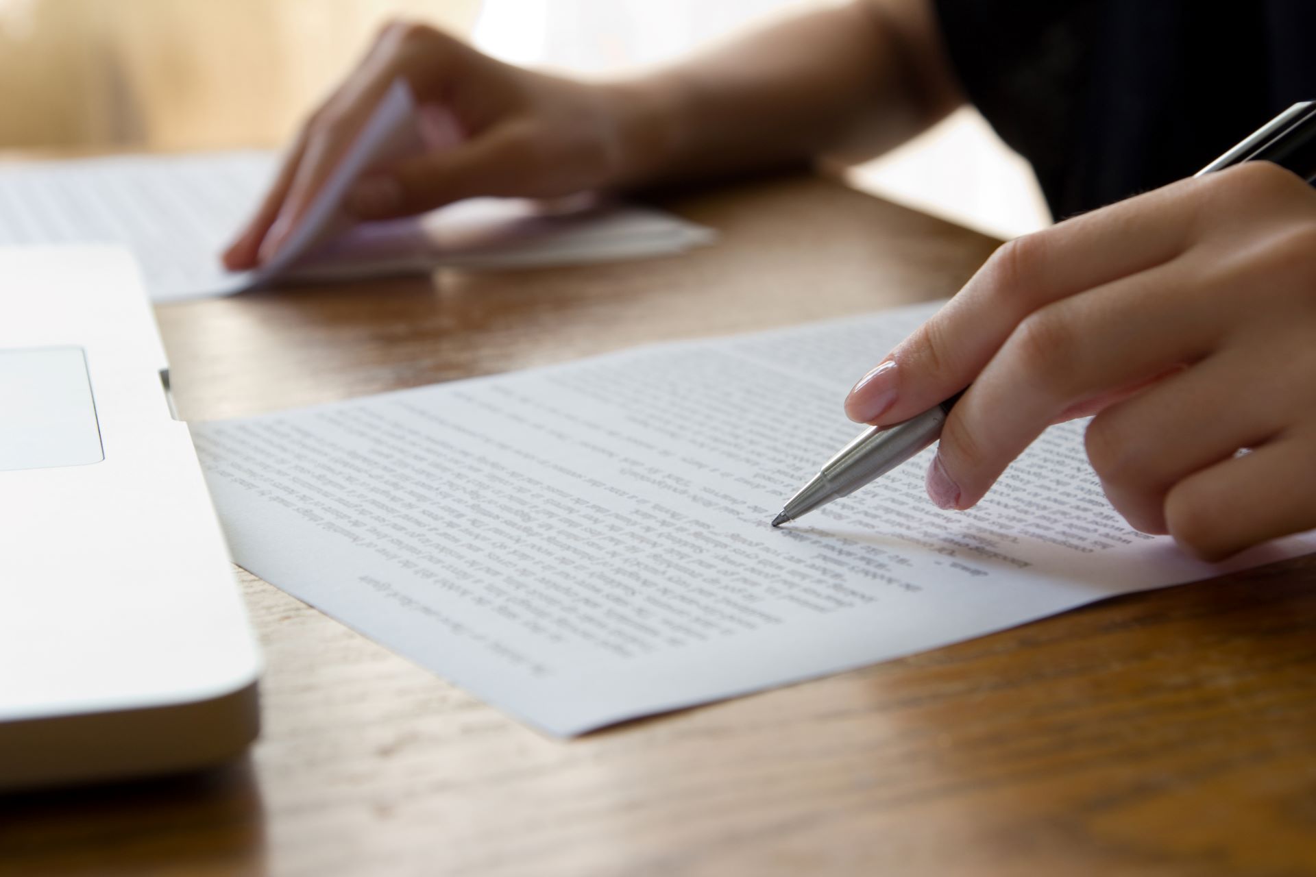 Person überarbeitet Text auf Papier mit Stift am Schreibtisch